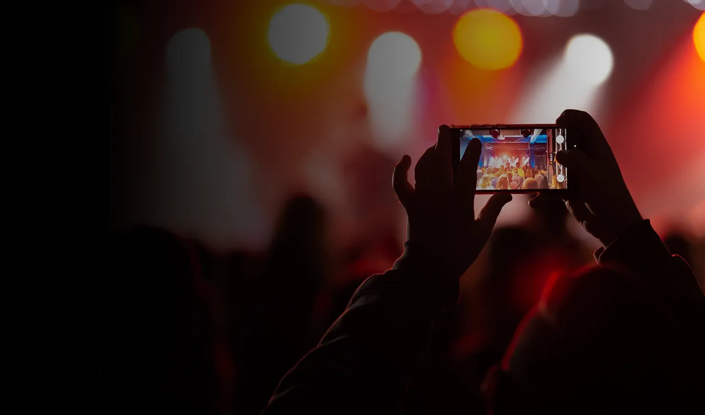 Pessoa gravando um concerto no celular, representando benefícios do estilo de vida